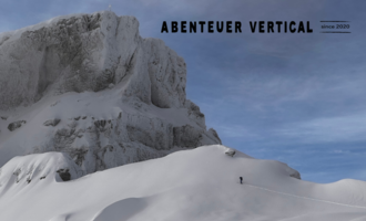 An impressive mountain landscape with snow-covered peaks and a clear sky. A person is exploring the alpine surroundings.