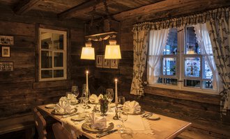 Ein gemütliches Restaurant mit einem schön gedeckten Tisch. Die warmen Lichter und Holzwände schaffen eine einladende Atmosphäre. | © Alpahotel Walserstuba GmbH Patrik Säly Photography