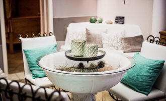 A stylish interior with a cozy table and comfortable chairs. Decorative items are on the table, creating a relaxed atmosphere. | © Verwöhn- & Wellnesshotel Walserhof| Aileen Melucci