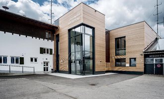 Ein modernes Gebäude mit Holzelementen und großen Fenstern. Es befindet sich in einer ländlichen Umgebung unter einem bewölkten Himmel. | © Bergrettung Riezlern | Gemeinde Mittelberg