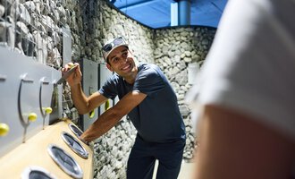 Ein moderner Flur mit großen Wandbildern und einem offenen Empfangsbereich. Die Wände sind mit sanften Farben und schönen Landschaften gestaltet. | © Kleinwalsertal Tourismus | Oliver Farys