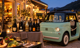 A stylish restaurant ambiance with a mint green Fiat and several bottles of sparkling wine. In the foreground, a beautifully set table with a delicious meal can be seen.