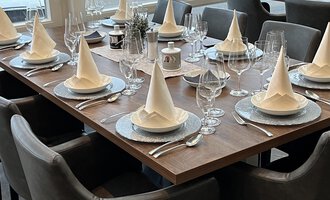 An elegantly set table with pointed fabric napkins and glasses. The atmosphere is festive and inviting.