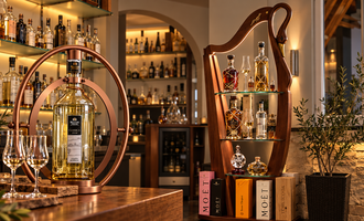 An elegant bar with a selection of high-quality spirits and glasses. In the background, the shelves are well-lit and decorated with various bottles.