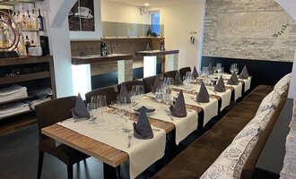 An elegant restaurant with a long table that is festively set. The atmosphere is modern and inviting.