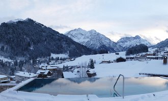 A beautiful view of snow-covered mountains and an infinity pool. The tranquil winter landscape radiates peace. | © Hotel Erlebach | Kristin Winter