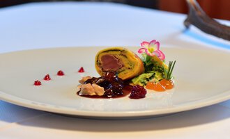 An artistically arranged dish on a white plate. It contains a filling of meat, accompanied by various sauces and garnishes. | © Alpenhof Jäger | Werbewind