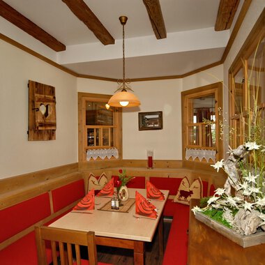 Ein gemütlicher Restaurantbereich mit roten Polstern und einem Holzstuben-Design. Die warmen Lichter und die Dekoration schaffen eine einladende Atmosphäre. | © Michl das Steakhaus | Johannes Littich