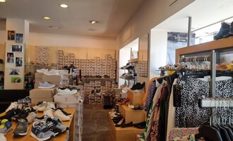 A shoe store with a variety of shoes and clothing. The shelves are full of shoe boxes and clothing hangs on clothes racks. | © Schuhhaus Schuster | Marietta Diehl