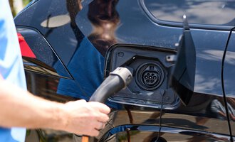 Eine Person lädt ein Elektroauto auf. Der Ladeanschluss ist geöffnet und eine Ladekabel wird eingesteckt. | © Kleinwalsertal Tourismus | Oliver Farys