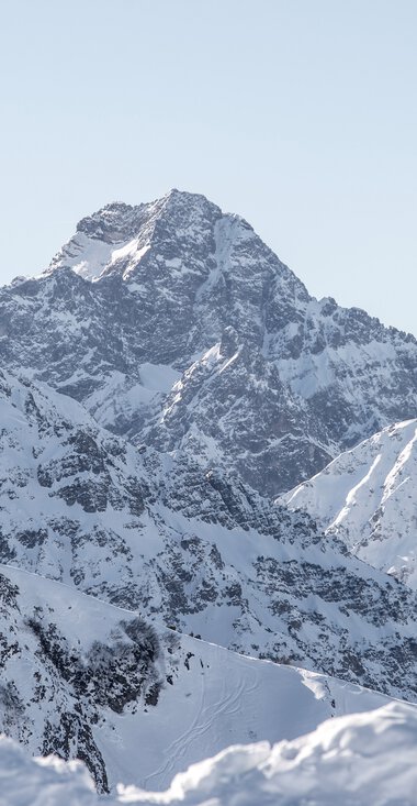 Panoramablick auf den verschneiten Widderstein-Gipfel und umliegende Berge in winterlicher Landschaft. | © Kleinwalsertal Tourismus eGen • Fotograf: Dominik Berchtold