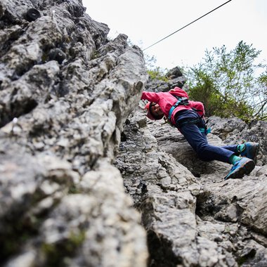 Person rock climbing on a rocky cliff at Bergschule Kleinwalsertal during summer 2023. | © Kleinwalsertal Tourismus eGen • Photographer: Oliver Farys