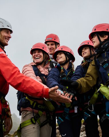Group photo during a via ferrata adventure in the mountains, with a mountain guide greeting or welcoming the group.
