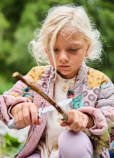 A young girl exploring with a stick outdoors during an adventure. | © Kleinwalsertal Tourismus eGen • Photographer: Oliver Farys