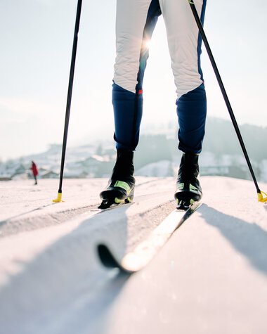 Cross-country skiers on the Schwarzwasserloipe in Kleinwalsertal, showing ski tracks in the snow with mountain scenery and a clear sky. | © Kleinwalsertal Tourismus eGen • Photographer: Oliver Farys
