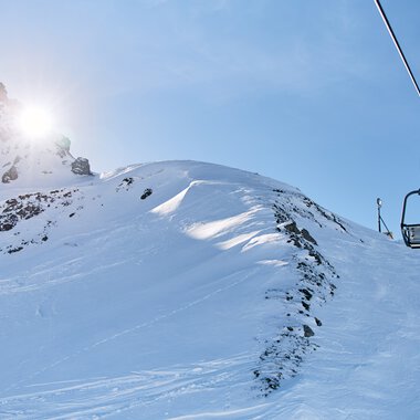 Schneebedeute Berge im Sonnenlicht bei einer Skitour, mit Skilift im Vordergrund, im Kleinwalsertal. | © Kleinwalsertal Tourismus eGen • Fotograf: Oliver Farys