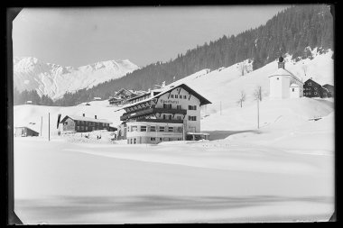 Snow-covered Sporthotel Walsertal in Baad with surrounding mountains and traditional buildings, black and white photo. | © Kleinwalsertal Tourismus eGen • Karl Max Kessler Archiv