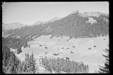 Historical black-and-white photo of Baad in Kleinwalsertal, featuring mountains and scattered houses in the landscape. | © Kleinwalsertal Tourismus eGen • Karl Max Kessler Archiv