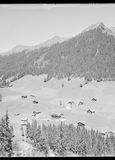 Historisches Schwarz-Weiß-Foto von Baad im Kleinwalsertal, mit Bergen und einzelnen Häusern in der Landschaft. | © Kleinwalsertal Tourismus eGen • Karl Max Kessler Archiv