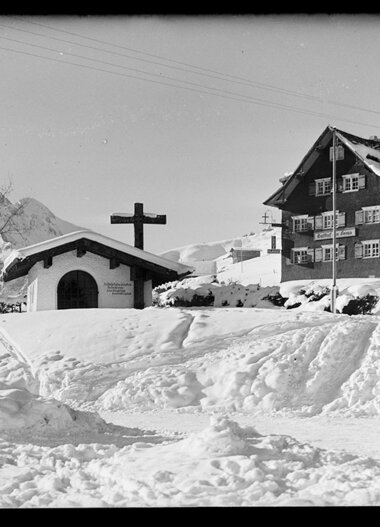 Snow-covered area with chapel and house in the mountains, winter, historic photograph. | © Kleinwalsertal Tourismus eGen • Karl Max Kessler Archiv