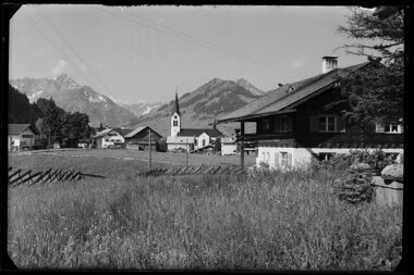 Historic photo of Riezlern showing the church and surrounding mountains, viewed from a meadow. | © Kleinwalsertal Tourismus eGen • Karl Max Kessler Archiv