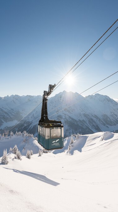 Gondelbahn im Wintertraum mit verschneiten Bergen und klarer Himmelssonne im Hintergrund. | © Oberstdorf · Kleinwalsertal Bergbahnen