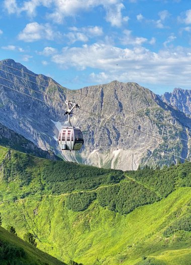 Sommerliche Kanzelwandbahn mit Gondeln im Alpenpanorama, grüne Hügel, Berge und blauer Himmel. | © Oberstdorf · Kleinwalsertal Bergbahnen