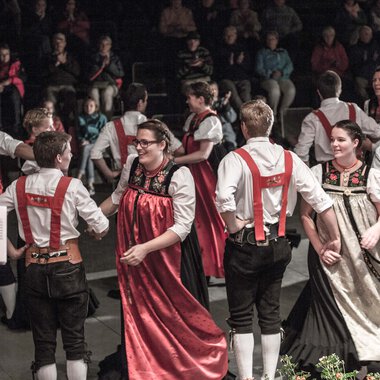 Young people in traditional costumes performing a dance at Alpenzauber event in a festival tent. | © Kleinwalsertal Tourismus eGen • Photographer: Frank Drechsel