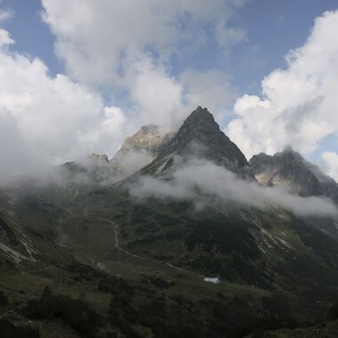 Mountain landscape with rugged peaks partly covered by clouds, showcasing stunning natural scenery. | © Kleinwalsertal Tourismus eGen • Photographer: Antje Pabst