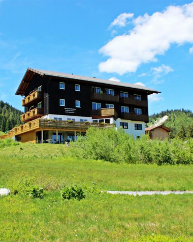 Modernes Gebäude in ländlicher Umgebung im Kleinwalsertal, umgeben von grünen Wiesen und Bergen, bei sonnigem Himmel. | © Kleinwalsertal Tourismus eGen