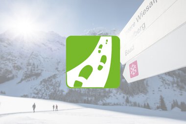 Wegweiser im Wintersportgebiet mit Fußgängern und verschneiten Bergen im Hintergrund. | © Kleinwalsertal Tourismus eGen