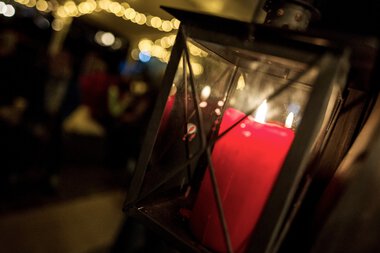 Eine Laterne mit einer roten Kerze, die im Dunkeln leuchtet, bei einer festlichen Veranstaltung im Adventsoccer. | © Kleinwalsertal Tourismus eGen • Fotograf: Dominik Berchtold